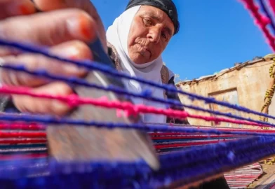 Evinin bahçesindeki tezgahta asırlık yöntemle kilim dokuyor