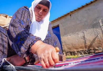 Evinin bahçesindeki tezgahta asırlık yöntemle kilim dokuyor