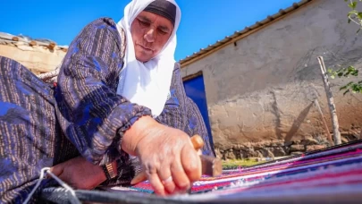 Evinin bahçesindeki tezgahta asırlık yöntemle kilim dokuyor