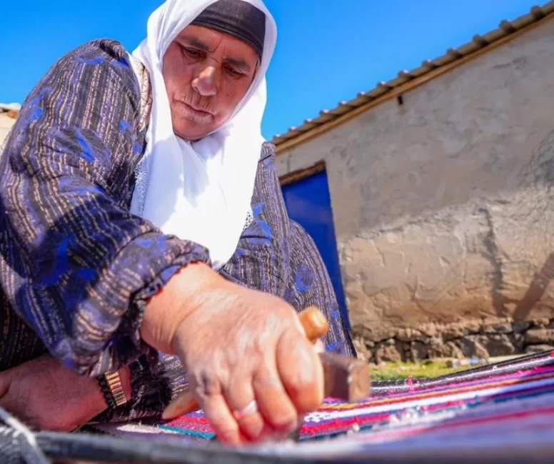 Evinin bahçesindeki tezgahta asırlık yöntemle kilim dokuyor